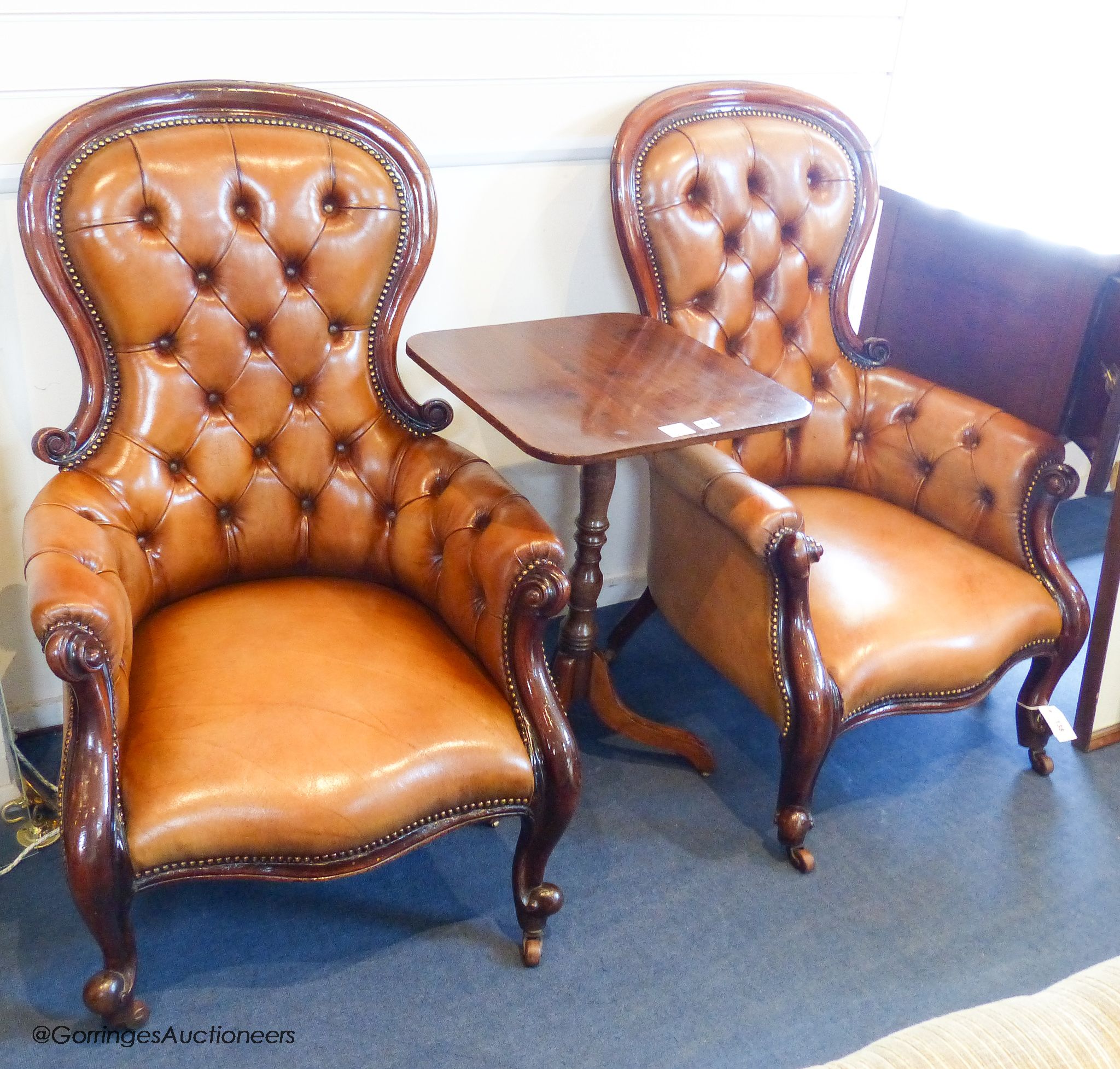 A pair of Victorian walnut and tan leather spoonback armchairs